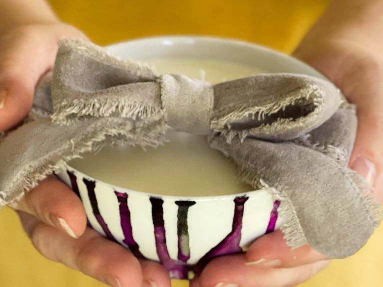candle gift, hands holding a candle wrapped in a bow