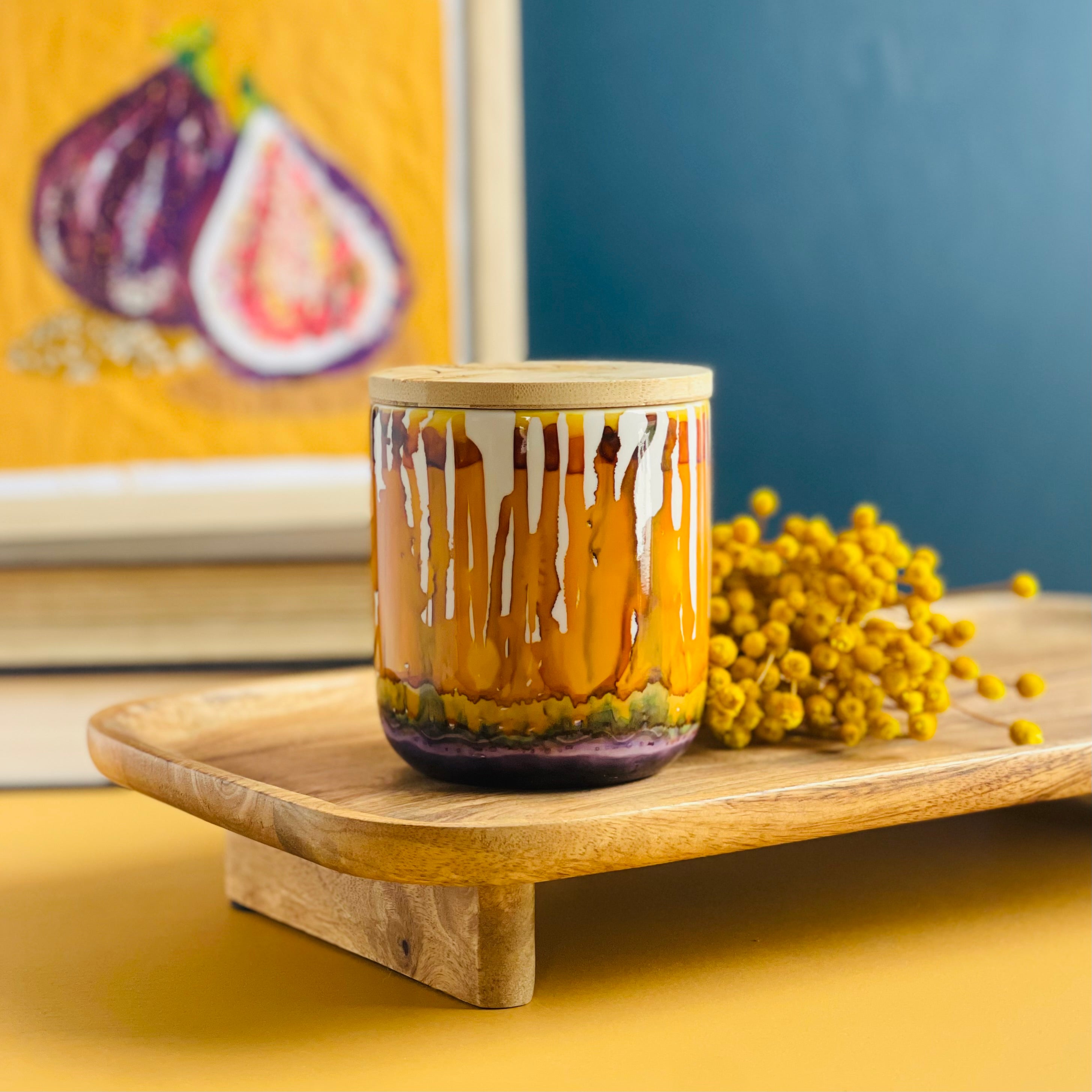 Tall, two wick ceramic candle handpainted in drippy oranges, warm yellows, and dusky purple