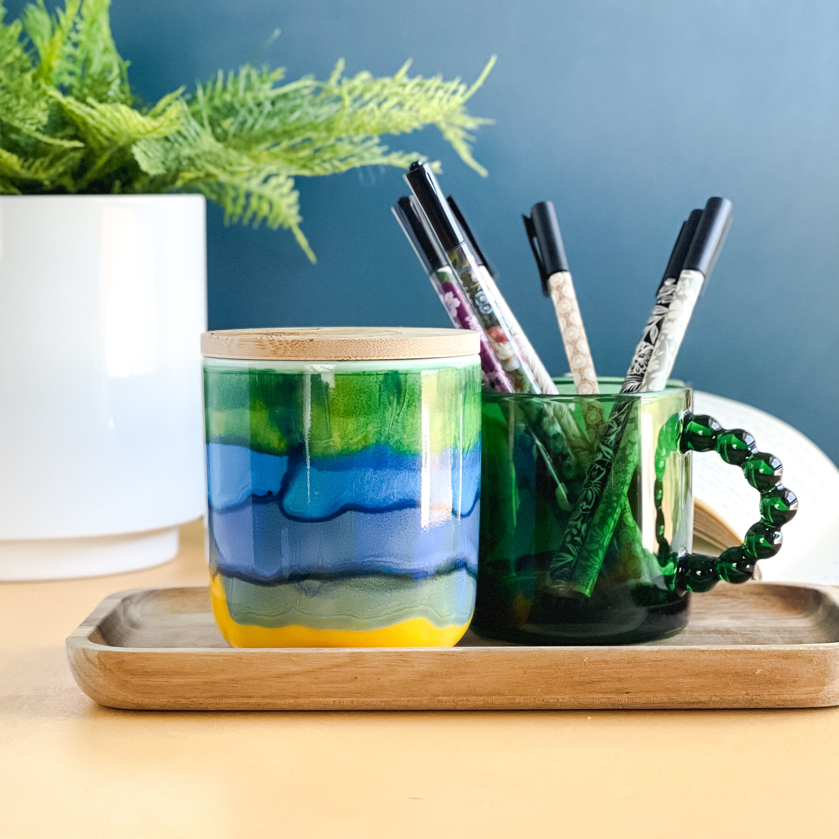 Tall, two wick ceramic soy candle handpainted in colorful bands of yellow, blue and green