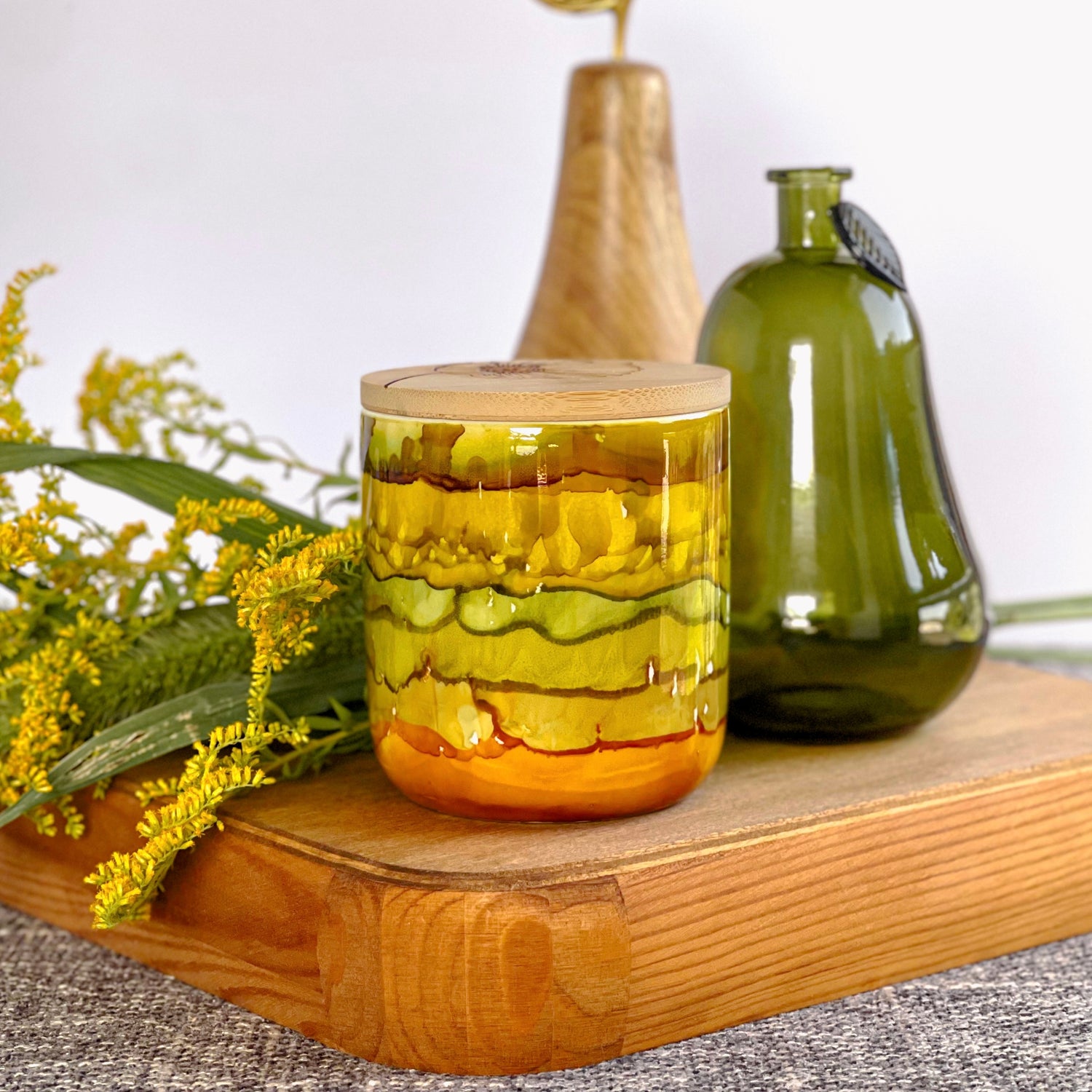 Handpainted ceramic candle in stacked shades of muted greens, golds, and amber, unique candles for fall