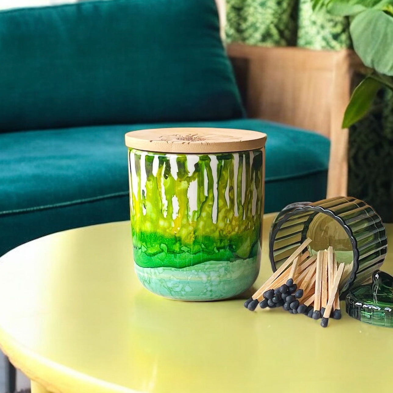 Tall, two wick ceramic soy candle handpainted in layers of mottled greens on a coffee table