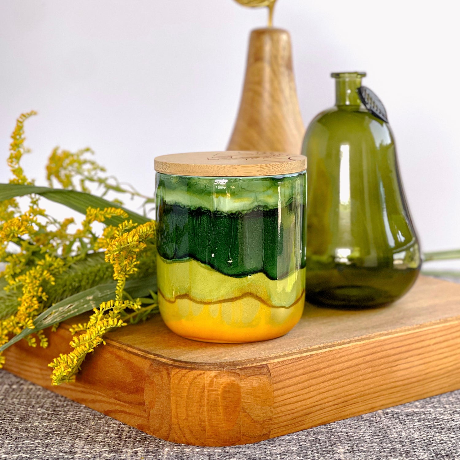 A wide deep green band with soft green and muted yellow surround this handpainted ceramic candle, unique candles for fall