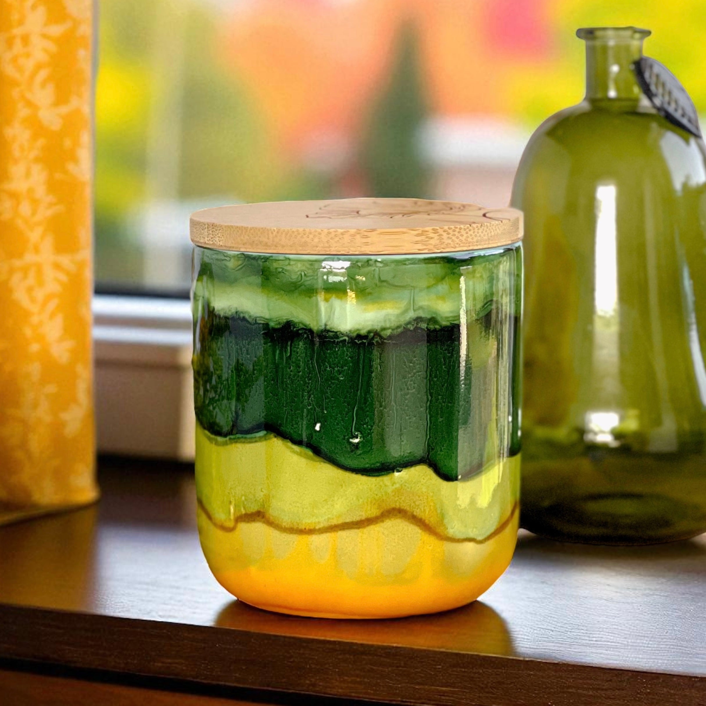 Tall, two wick ceramic candle handpainted in bands of mossy and forest greens with a base of warm yellow