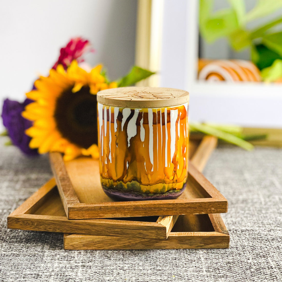 Tall, two wick ceramic candle handpainted in drippy oranges, warm yellows, and dusky purple