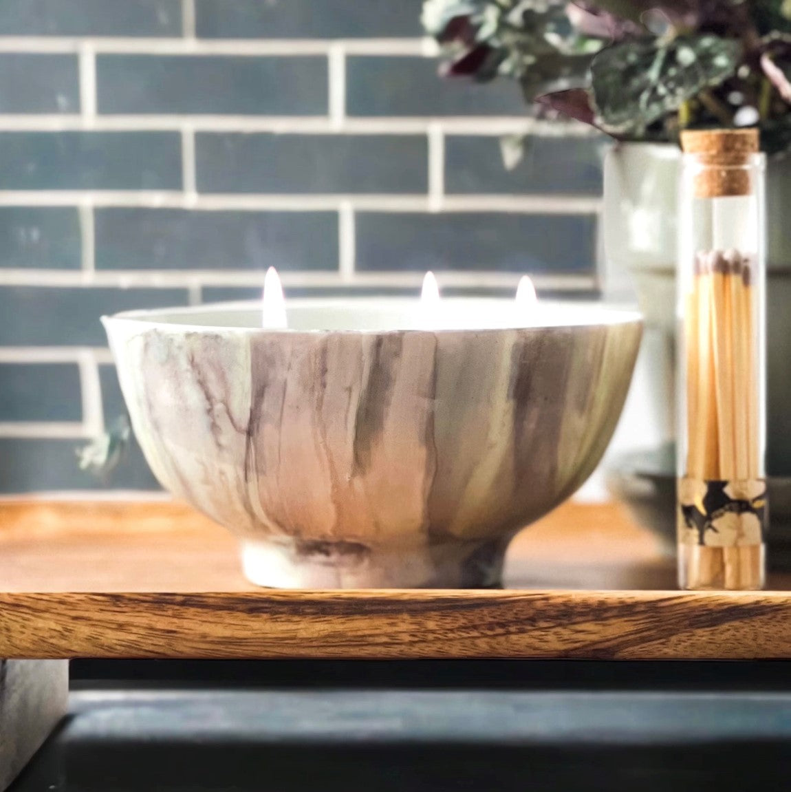 Ceramic three wick candle handpainted in soft gray and pale mint lit on a tray