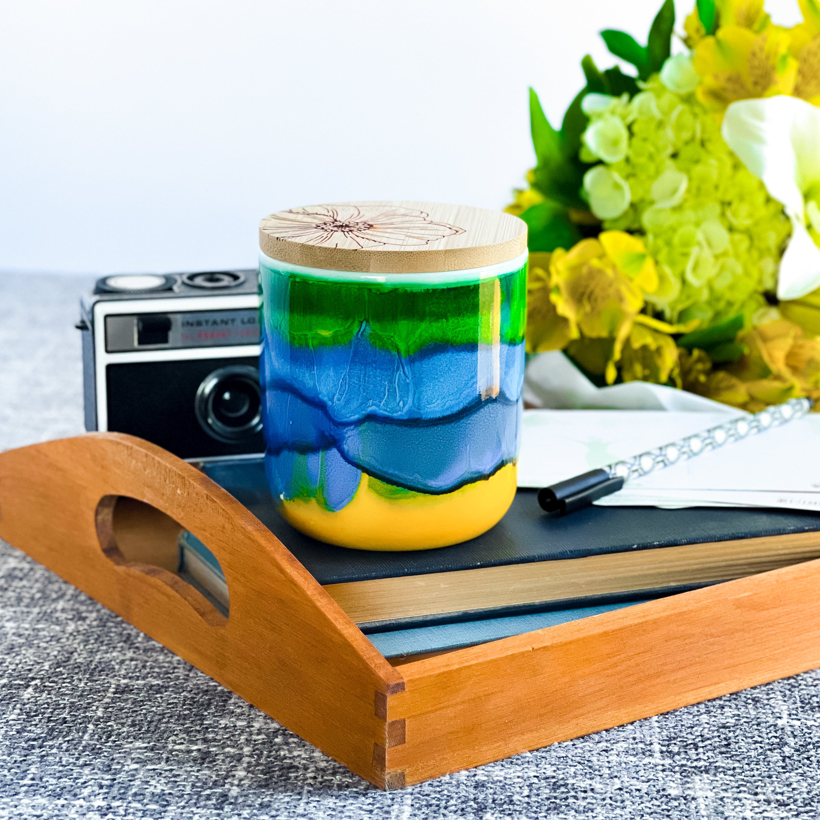 Tall, two wick ceramic soy candle handpainted in colorful bands of yellow, blue and green