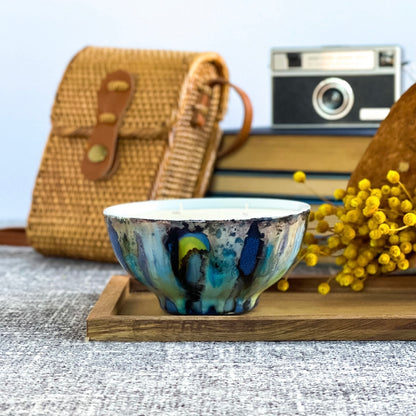 Handpainted, three wick ceramic candle in dramatic blues and grays with pops of yellow