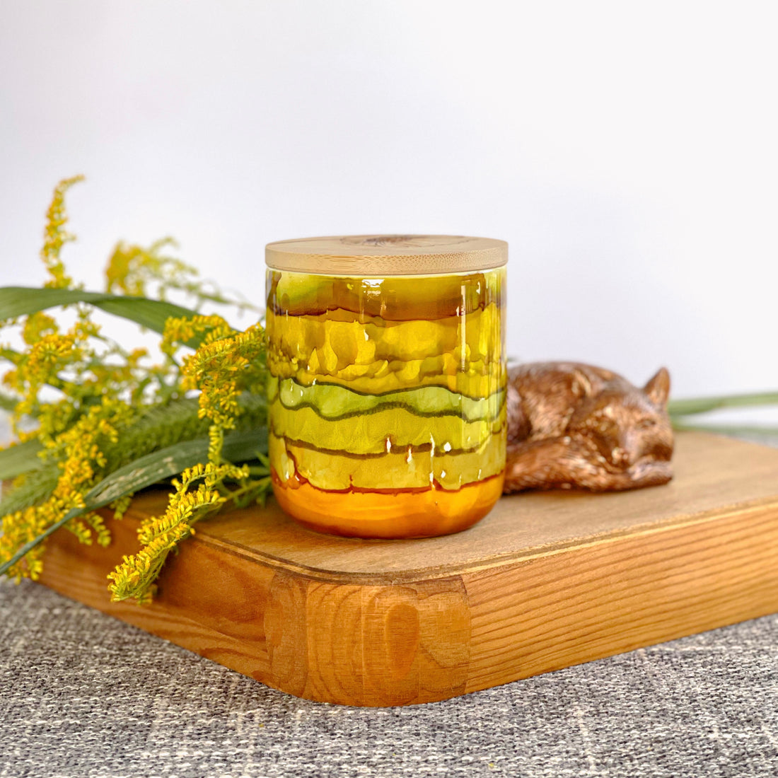 Handpainted ceramic candle in stacked shades of muted greens, golds, and amber, unique candles for fall