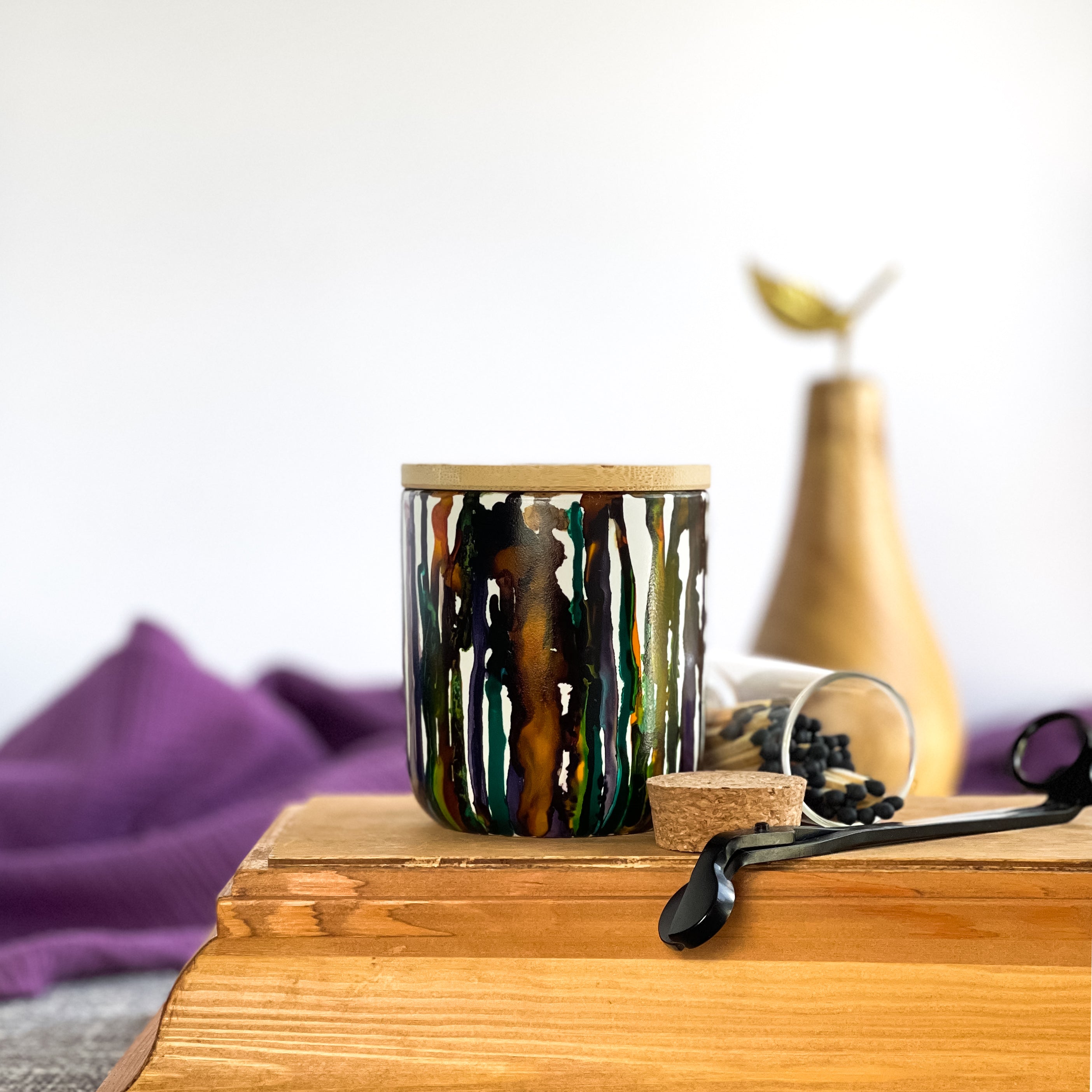 Tall, two wick ceramic soy candle handpainted in drippy yellows, warm browns, with touches of leafy green, teal and wine purple