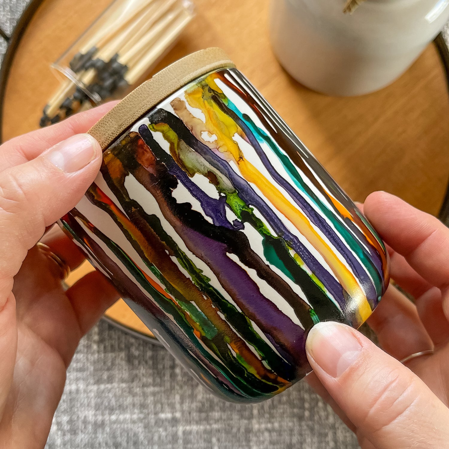 Tall, two wick ceramic soy candle handpainted in drippy yellows, warm browns, with touches of leafy green, teal and wine purple