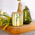 Tall, two wick ceramic candle handpainted in drippy soft teals and deep yellows